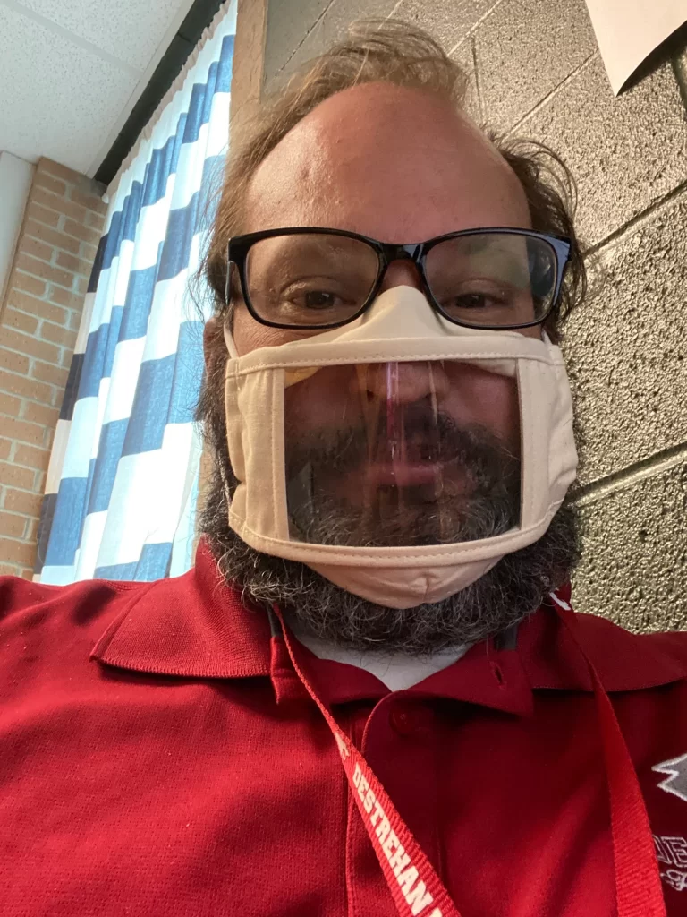 A teacher with a mask teaching during covid.